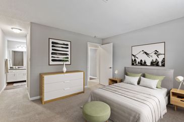 A Villages at Spring Hill apartment bedroom with carpeting and an en-suite bedroom.